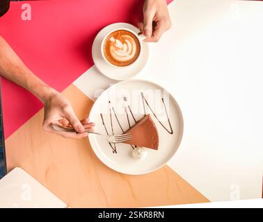 Ein Mann, der ein Stück Schokoladenkuchen mit Sahne und einer Tasse Kaffee serviert. Stockfoto