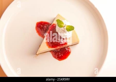 Oberer Schuss eines Erdbeerkäsekuchen mit einem Schuss Sahne und Minzblatt darauf. Stockfoto
