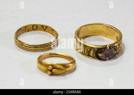 EMBARGOED TO 00.01 13/02/2025  London, UK.  12 February 2025.  (L to R) A 17th century ring with internal engraving of ‘LOVE GOD’, a Roman child ring, and a 1450s gold ring set with a pink spinel ‘pour amor say donne’ – for love I am given. They are some of the  mudlarked finds set for display in London Museum Dockland’s Secrets of the Thames exhibition, opening 4 April 2025. Credit: Stephen Chung / Alamy Live News Stockfoto