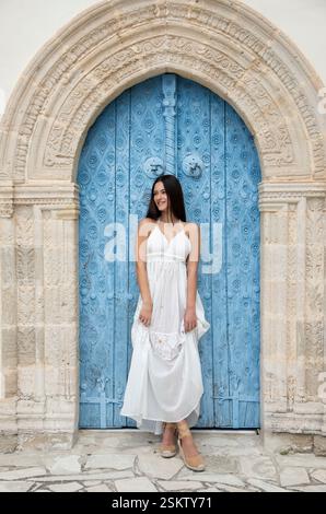 Junge Frau, die im Urlaub vor einer blauen Tür steht Stockfoto