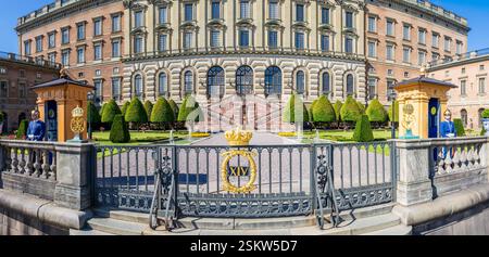 Eingang des Logården-Gartens des Königlichen Palastes in Stockholm, Schweden, mit einer vergoldeten Krone auf dem Zaun, flankiert von zwei Kaisergarden. Stockfoto