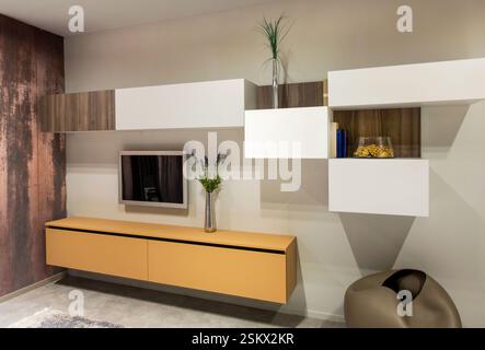 Stilvolle und moderne Wohnzimmereinrichtung mit Wandablagen, fernseher und minimalistischer Einrichtung Stockfoto