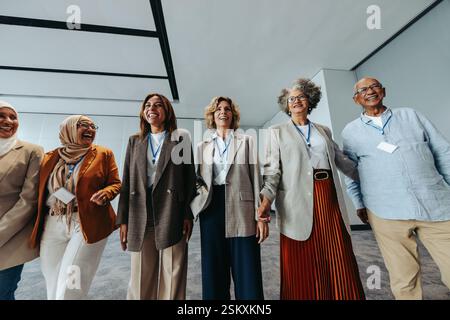 Eine multiethnische Gruppe von Geschäftsleuten, die an einer Konferenz teilnehmen und Teamarbeit und positive Interaktionen präsentieren. Sie sind engagiert und lächeln, reflektieren Stockfoto