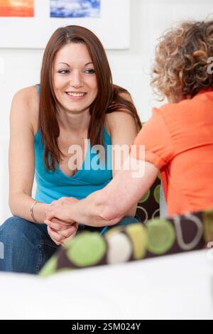 Eine junge Frau, die einen emotionalen Rat von einem freundlichen Berater nimmt. Stockfoto