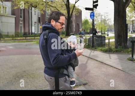 Ein Vater, der sein Kind in einem Känguru trägt Stockfoto