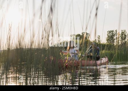 Glückliches Paar, das im Sommer eine Kanufahrt auf dem See genießt und sich inmitten der wunderschönen grünen Natur entspannt. Konzepte für Kanufahrten. Stockfoto