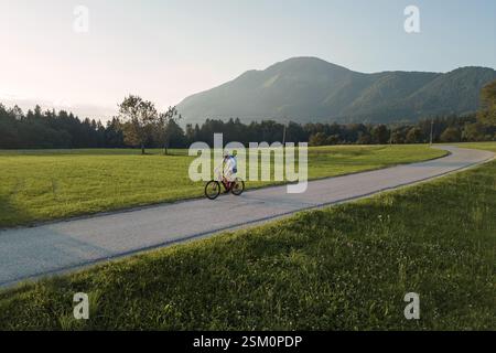 Man fährt mit dem Elektro-Mountainbike entlang des Weges in einer fantastischen ländlichen Landschaft, aus der Vogelperspektive. Natur- und Erholungskonzepte. Stockfoto