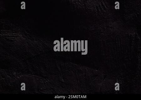 Die Textur der schwarzen Steinoberfläche. Raue, unebene Wand mit Kratzern und Platz zum Kopieren. Hochwertige Fotos Stockfoto