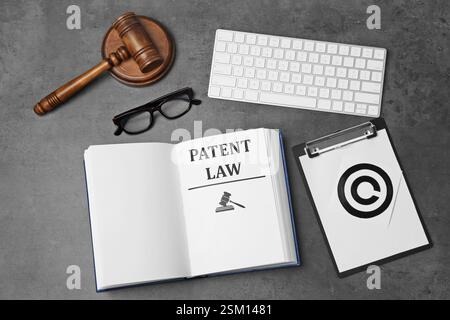 Lizenz. Patentgesetzbuch, Papier mit Copyright-Symbol, Computertastatur und Richter-Hammer auf grauem Tisch, flache Lay Stockfoto