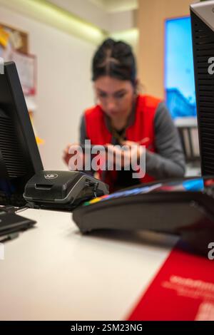 Cremona, Italien - 8. Februar 2024 Vodafone-Verkäuferin unterstützt Kunden bei der Einrichtung des Smartphones in einem lebhaften Vodafone-Geschäft und präsentiert die neuesten Mobs Stockfoto