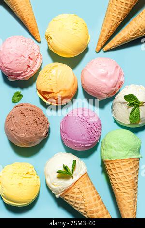 Verschiedene Eiskugeln auf blauem Hintergrund, Draufsicht. Verschiedene Eissorten oder Eis mit Waffelkegel, gesundes Sommerdessert kreatives Konzept. Stockfoto