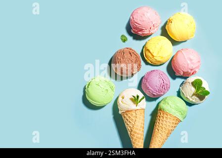 Verschiedene Eislöffel auf blauem pastellfarbenem Hintergrund, Draufsicht, Kopierraum. Viele Bio-Eislöffel aus italienischem Eis mit Minzblättern und Waffel Co Stockfoto