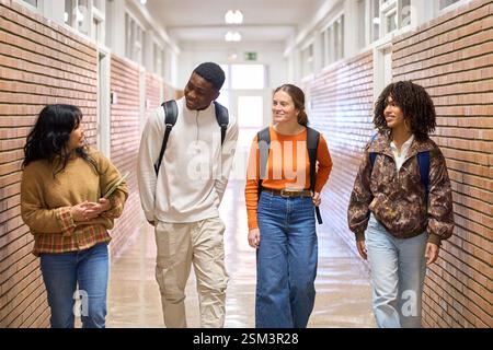 Glückliche Studenten gehen und reden im Universitätskorridor Stockfoto