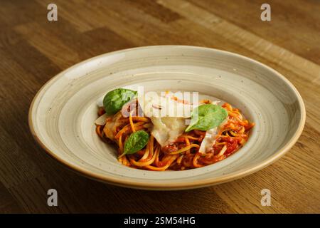 Eine wunderschön überzogene Portion Spaghetti mit reichhaltiger Tomatensauce, garniert mit frischen Basilikumblättern und geriebenem Parmesankäse. Das Gericht ist ser Stockfoto