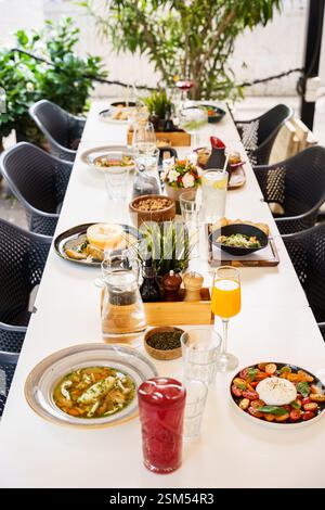 Ein wunderschön gestalteter Brunch-Tisch im Freien mit einer Vielzahl von Gerichten und Getränken, einschließlich Salaten, Suppen, frischen Säften und Vorspeisen. Die Stockfoto