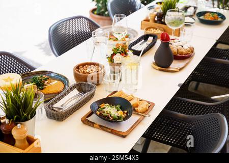 Ein wunderschön gestalteter Brunch-Tisch im Freien mit einer Vielzahl von Gerichten und Getränken, einschließlich Salaten, Suppen, frischen Säften und Vorspeisen. Die Stockfoto