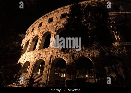 In warmem Licht getauchte Steinruinen, umrahmt von Bäumen in einer dramatischen nächtlichen Umgebung. Stockfoto