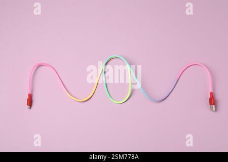 USB-Ladekabel auf rosa Hintergrund, Draufsicht Stockfoto