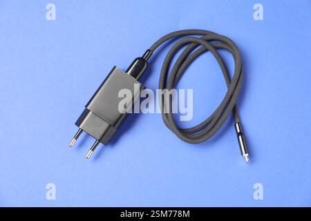 USB-Netzteil mit Ladekabel auf blauem Hintergrund, Draufsicht Stockfoto