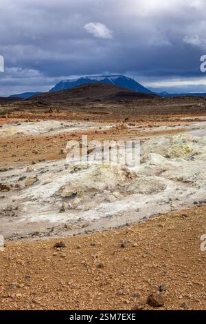 Vulkanische Landschaft von Hverir, Myvatn geothermisches Gebiet in Island, mit orange schwefelhaltigen Böden, Felsen und Steinen, vulkanischem Krater im Hintergrund. Stockfoto