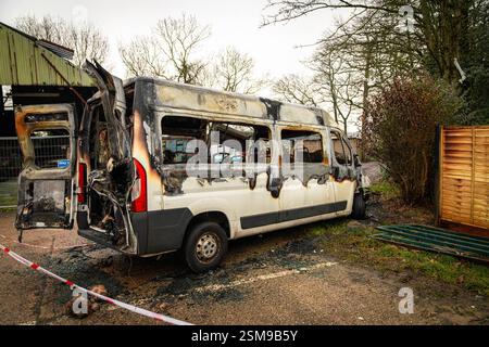 Weißer Van brannte völlig aus, parkte in der Nähe eines Holzzauns und eines Metalltors, mit einem rot-weißen Warnband auf dem Boden Stockfoto