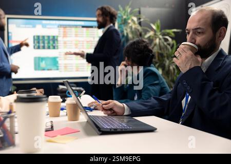 Unternehmensanalyst arbeitet an der Entwicklung von Geschäftsstrategien und -Zielen, untersucht Marktdynamik und Kundenfeedback auf interaktiven Boards. Das Team des Unternehmens nimmt an einer Entwicklungskonferenz Teil. Stockfoto