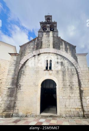 Kotor, Montenegro - 2. Juli 2024: Alte historische Innenstadt. Fassade der Kirche Saint Luke mit ihren Glocken oben vor blauer Wolkenlandschaft Stockfoto