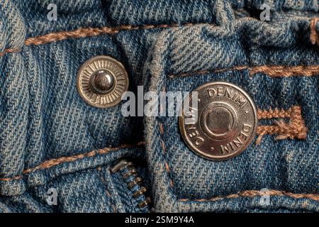 Knopf- und Nähte eines Denim-Kleidungsstücks. Jeansstoff im Detail. Stockfoto