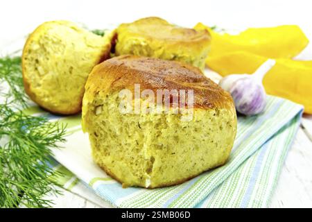 Kürbis Scones mit Knoblauch und Dill auf einem Handtuch, gelb Kürbisscheiben auf dem Hintergrund der Holzbretter Stockfoto
