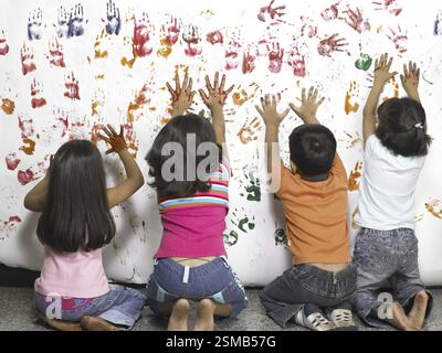 Südasiatische indische Jungen und Mädchen, die Aquarellhandabdrücke auf Papier in Kindergärten machen MR Stockfoto