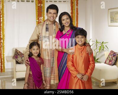 Eltern mit Kindern in traditionellem Tragen stehen im Haus MR#702R, MR#702S, MR#702T, MR#702U Stockfoto