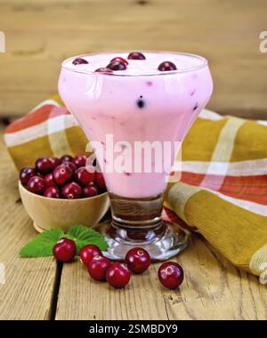 Dicker Joghurt in einem Glasbecher mit Preiselbeeren, Serviette, Preiselbeeren in einer Schüssel, Minze auf einem Holzbrett Hintergrund Stockfoto