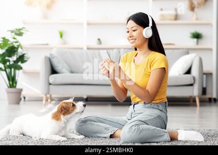 Fröhliche asiatische Frau, die Foto von ihrem niedlichen Hund Stockfoto