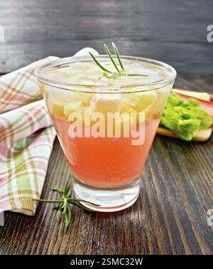 Limonade mit Rhabarber und Rosmarin in einem Glas, Stiele und ein Blatt eines pflanzlichen, Serviette auf einem Holzbrett Hintergrund Stockfoto