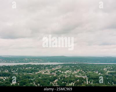 Üppiges Grün entfaltet sich unten mit einem ruhigen See, der unter einem bewölkten Himmel sichtbar ist, und fängt das Wesen eines ruhigen Nachmittags ein. Stockfoto