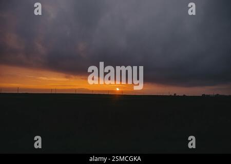 Die Sonne untergeht hinter Wolken und erzeugt einen dramatischen, stimmungsvollen Himmel Stockfoto