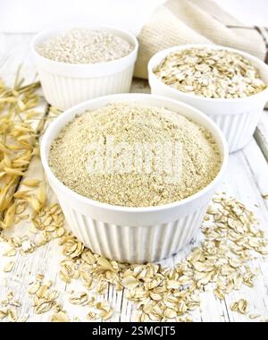Mahlzeit Hafer, Kleie, Hafer Flocken in drei weißen Schalen, Hafer Stiele, Handtuch auf einem Hintergrund von Holzbrettern Stockfoto
