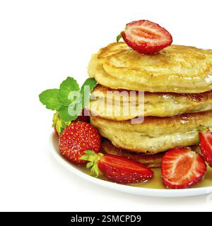 Ein Stapel Pfannkuchen mit Erdbeeren, Minze und Honig auf einer weißen Platte isoliert auf weißem Hintergrund Stockfoto