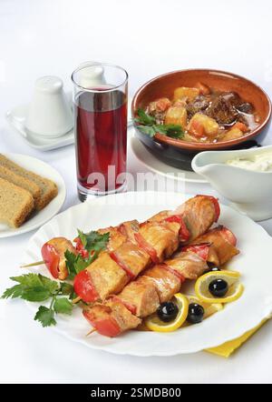 Stillleben mit Ihrem Tisch mit Suppe in Keramik Töpfe, Fleisch auf Spieße und ein Glas Saft. Bild mit weißem Hintergrund. Russische Küche Stockfoto