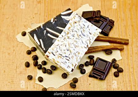 Zwei Tische hausgemachte Seife beige und braun, Schokoladenchips, Zimt, Kaffeebohnen auf altem Papier auf dem Hintergrund von Holzbrettern Stockfoto