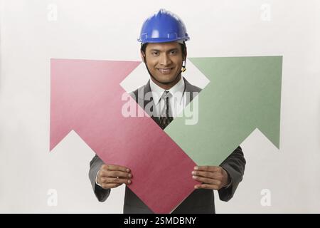 Geschäftsmann mit blauen Helm mit großen Größe, die grüne und rote Farbe Papier Pfeil in beide Herr #703T Hände holding Stockfoto