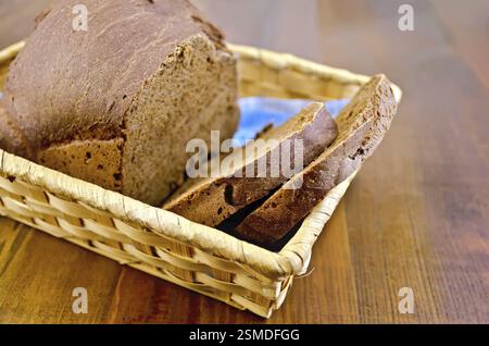 Ein Laib geschnittenes Roggen Scheiben selbstgebackenes Brot in einem Weidenkorb auf Holzbrettern Hintergrund Stockfoto