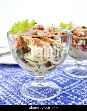 Salat mit Garnelen, Avocado, Tomaten, grüner Salat in ein Glas Becher, ein Teller vor dem Hintergrund einer Leinen Tischdecke Stockfoto