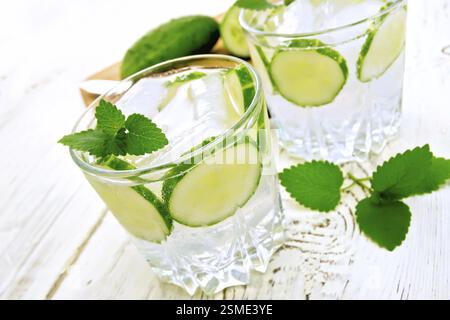 Limonade mit Gurke und Minze in zwei Gläser, ein Messer, eine Gurke auf einem weißen Hintergrund Holzbrett Stockfoto