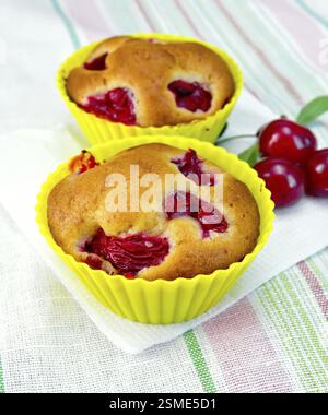 Cupcakes mit einer Kirsche in Dosen, Zimt auf einem weißen Papiertuch auf dem Hintergrund einer Leinentischdecke Stockfoto