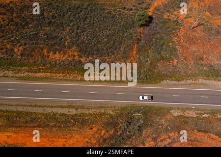 Ein weißer Pickup fährt entlang des Barrier Highway in Little Topar, New South Wales, Australien, durch eine trockene Landschaft bei klarem Tageslicht. Stockfoto