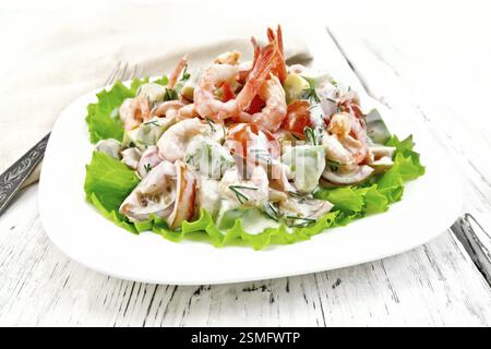 Salat mit Garnelen, Avocados, Tomaten und Mayonnaise auf den grünen Salat auf einen Teller, Servietten, Gabel auf dem Hintergrund der hölzernen Tisch Stockfoto