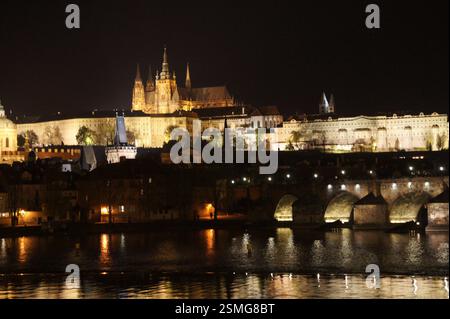 Prager Burg, ein majestätischer Gebäudekomplex, der nachts beleuchtet ist. Die Burg dominiert die Skyline der Stadt mit ihren Türmen und Türmen, die sich in der Stadt spiegeln Stockfoto