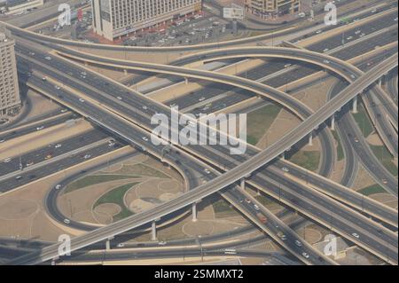 Ein Blick aus der Luft auf Dubai zeigt eine geschäftige Autobahnkreuzung. Ein komplexes Netz von Straßen und Brücken schlängelt sich durch die Stadt und zeigt das geschäftige e Stockfoto