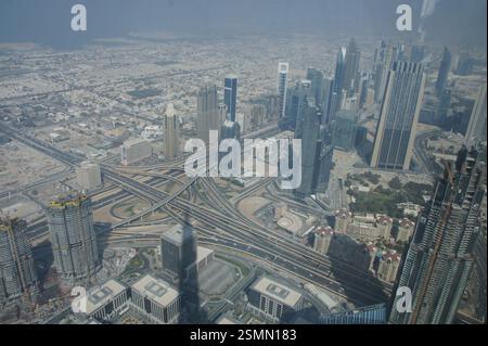 Ein Blick aus der Vogelperspektive auf Dubai offenbart eine geschäftige Kreuzung. Hoch aufragende Wolkenkratzer und Glasriesen bilden den chaotischen Tanz der Fahrzeuge, die in allen hineinströmen Stockfoto